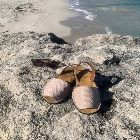 Pair of sandals on a rocky surface with a beach in the background