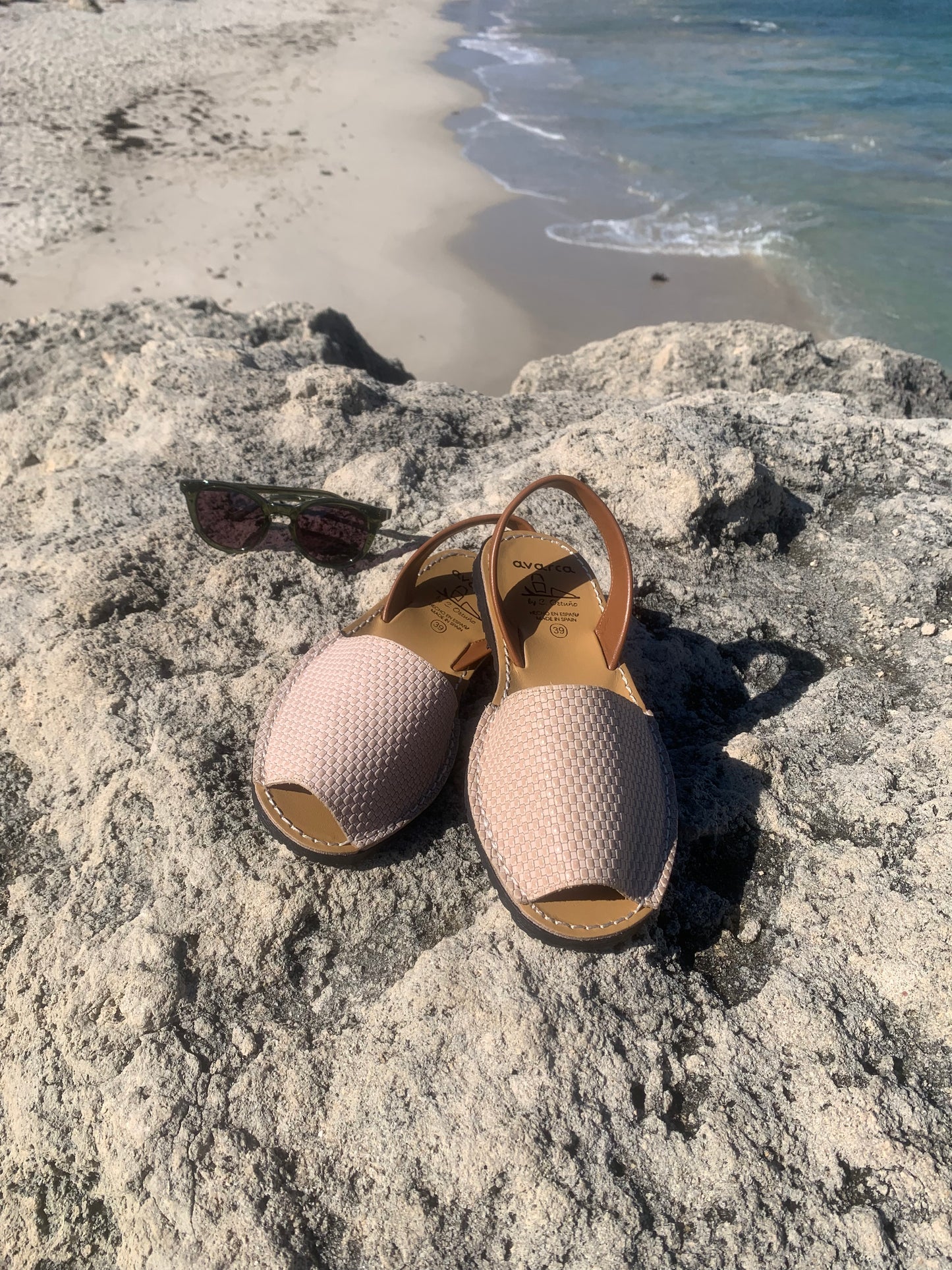 Pair of ladies sandals on a rocky surface with a beach in the background